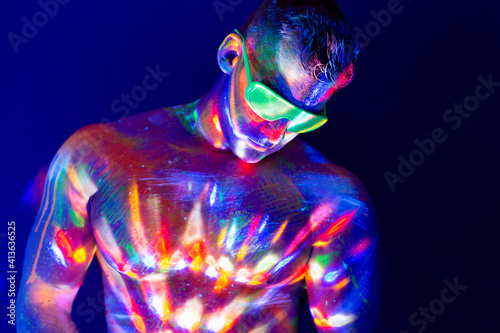 .Portrait of a pumped-up man at a disco. Fluorescent paint on face in with UV light