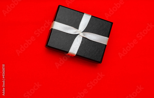 Small rectegular black gift box on a red background, top view