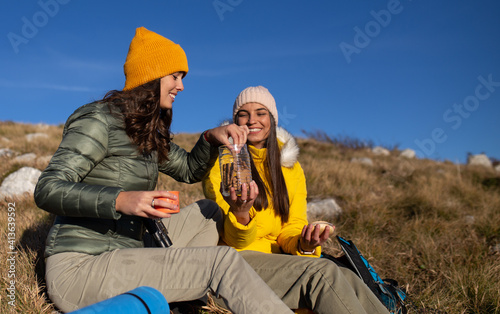 Two young women are resting from hiking and eating cookies. © Red Riding Hood