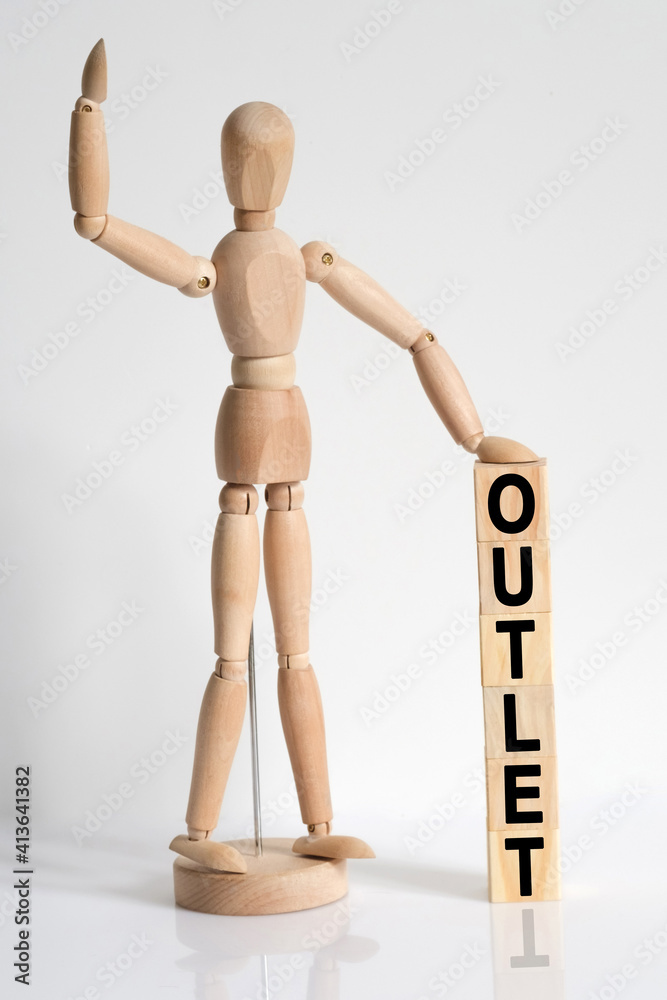 The wooden man raised his hand, and under his left hand he has cubes with the inscription - OUTLET The wooden man raised his hand, and under his left hand he has cubes with the inscription - OUTLET