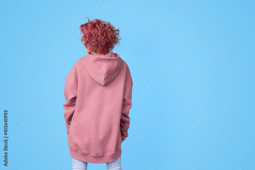 Girl with pink curly hair wearing oversized pink casual hoodie and jeans  standing backwards Stock Photo | Adobe Stock