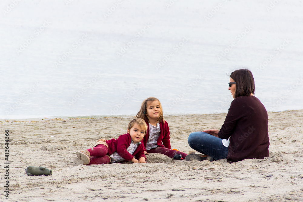 family sitting on the beach on a winter's day