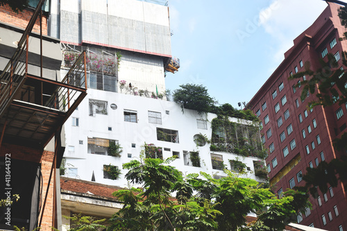 Saigon, Vietnam - January 6 2020: Apartment building with varying sized windows and green foliage and plants 