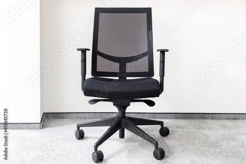 Fotografija Modern black office chair in an empty office against white wall on gray carpet