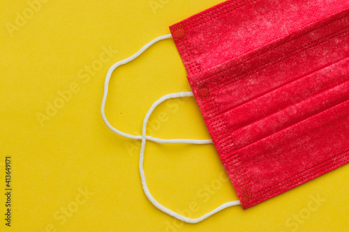 Disposable red surgical masks to prevent infection with the corona virus, on a yellow background