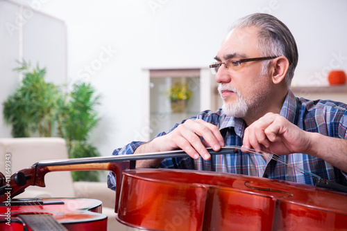 Obraz na plátně Senior male repairman repairing musical instruments at home