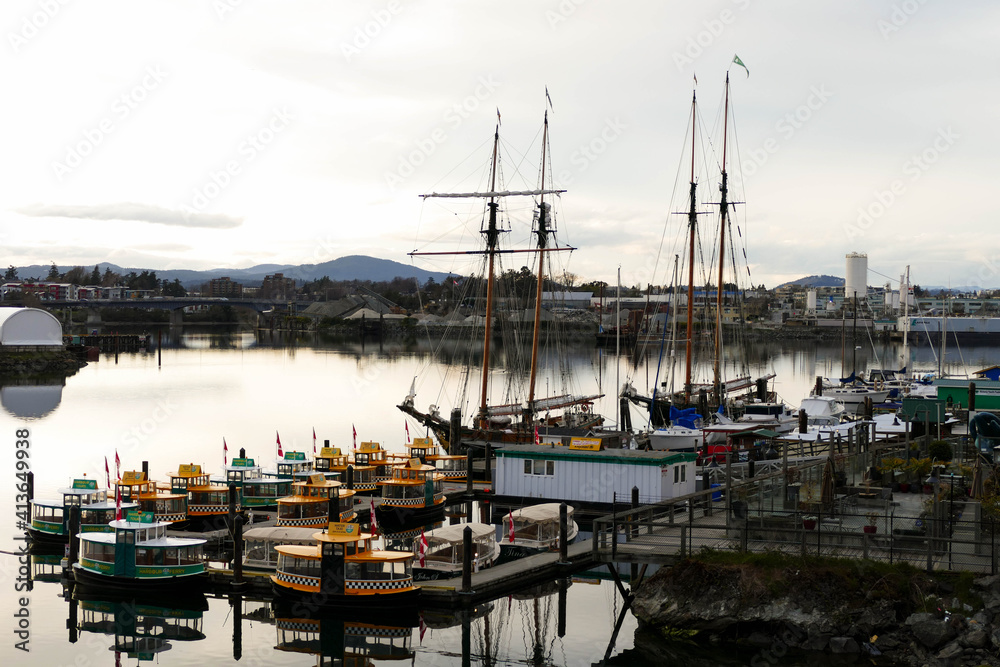 A calm harbor in Victoria with water-taxis and old sailing ships