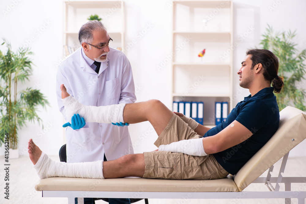 Fototapeta premium Young injured man visiting old doctor traumatologist