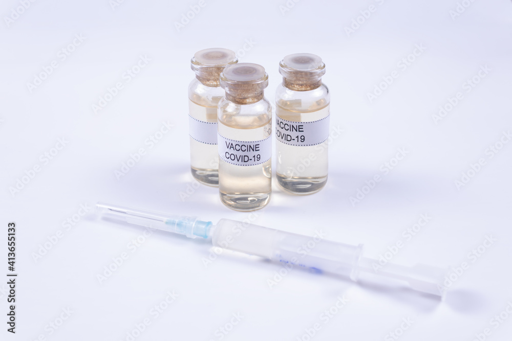 on a white background there is a syringe behind it there are three vials of covid-19 vaccine on a white background there is a syringe behind it there are three vials of covid-19 vaccine
