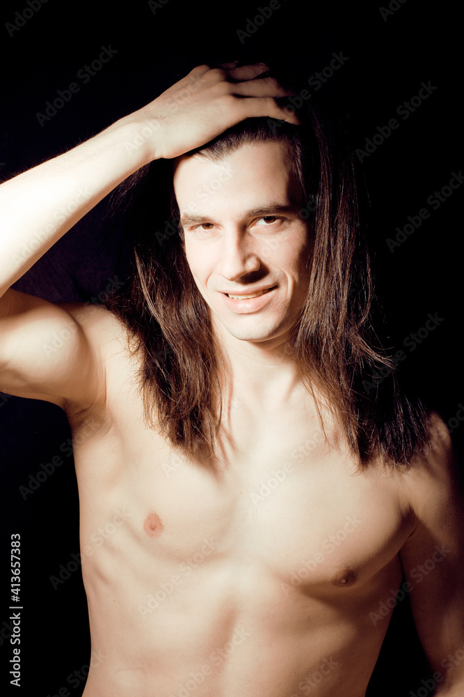 handsome young man with long hair naked torso on black background smiling, lifestyle people concept handsome young man with long hair naked torso on black background smiling, lifestyle people concept