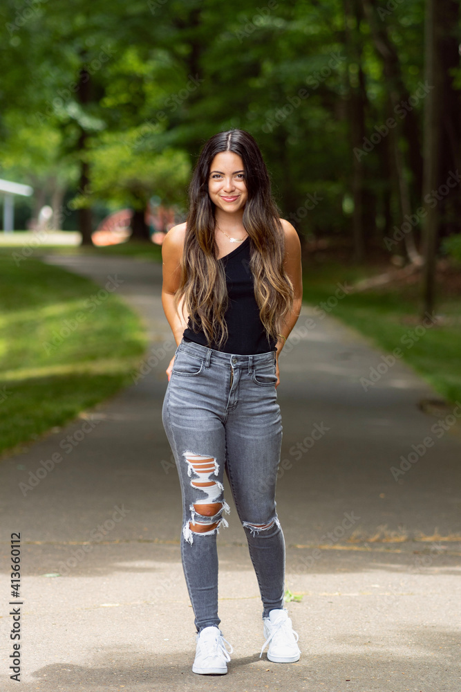 Portrait of a beautiful smiling young woman in park modeling jeans Portrait of a beautiful smiling young woman in park modeling jeans