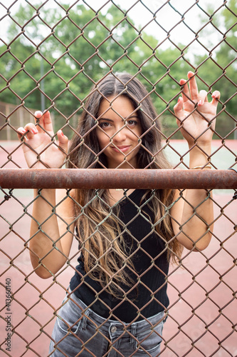 Beautiful smiling brunette model behind chain fence