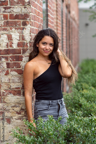 Beautiful young woman on brick wall outside smiling portrait