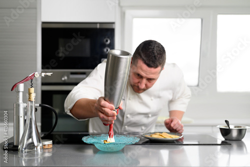 Slika na platnu Professional chef holding a foam siphon in a restaurant kitchen
