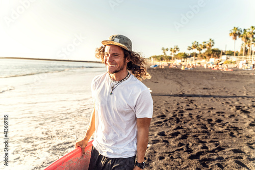 Happy handsome man having fun  walking with surfboard on the beach. Smiling surfer. Hobby. Summer time. Island vibes. Real people lifestyle and extreme sport concept