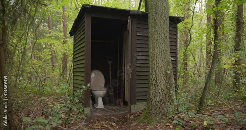 Outdoor toilet in the woods. Restroom in a wooden shed in a forest.Outdoor toilet in the middle of a forest. Outhouse between the trees. A dated lavatory in nature. WC in woodlands. Toilet in a shack. photo