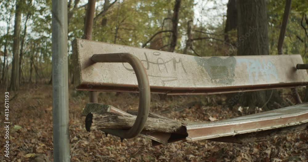 Close up shot of a makeshift bench in a forest, with graffiti scribbled on its rusty surface Close up shot of a makeshift bench in a forest, with graffiti scribbled on its rusty surface