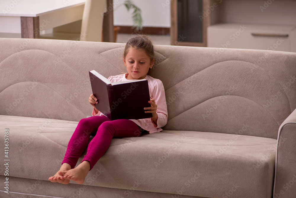 Naklejka premium Small girl reading book at home
