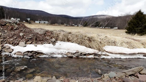 Slow dolly right down freshwater stream in the Catskill mountains with rural neighborhood in background photo