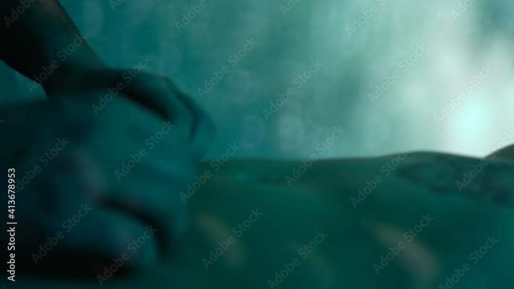 Person performing relaxing massage on tattooed woman belly with ambient lights that create relaxing atmosphere Person performing relaxing massage on tattooed woman belly with ambient lights that create relaxing atmosphere