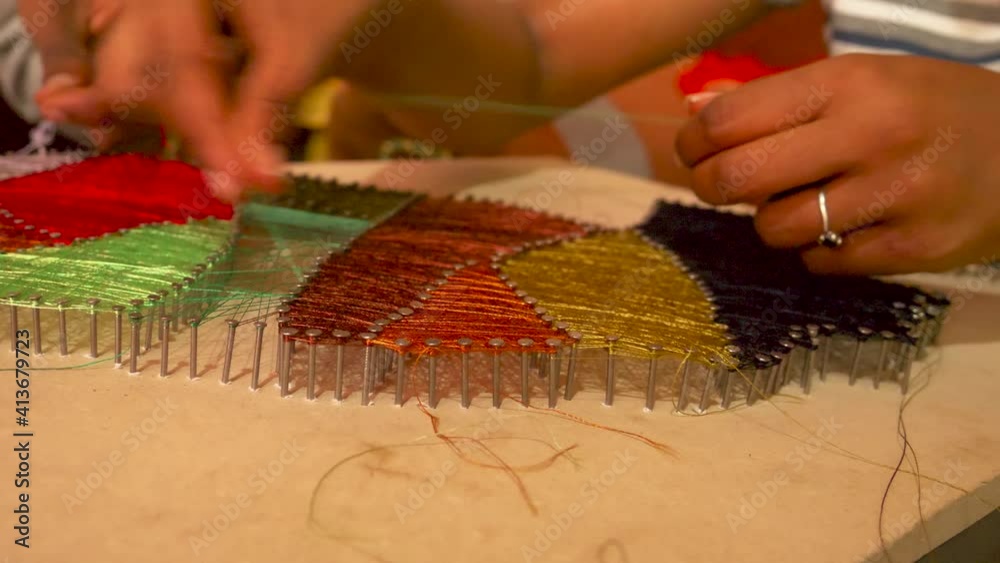 A girl in Rural area in Ethiopia is doing string art with help of her brother, trying to finish this peace and ready to sell