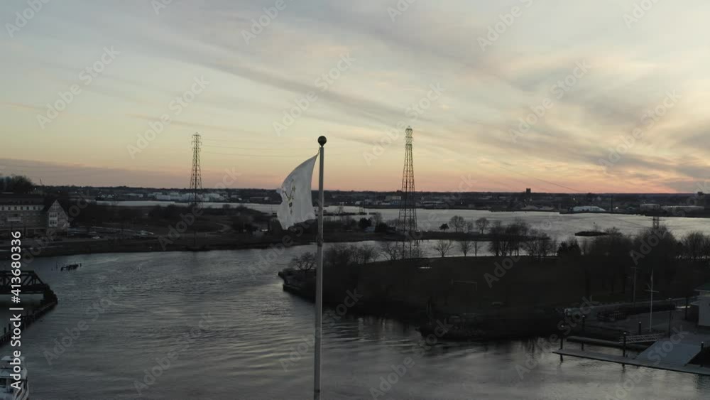 Close aerial view of the Rhode Island State flag flying over a harbor at sunset Close aerial view of the Rhode Island State flag flying over a harbor at sunset