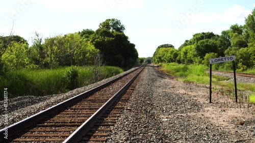 Train Tracks leading off into a lush abandoned and overgrown town. photo