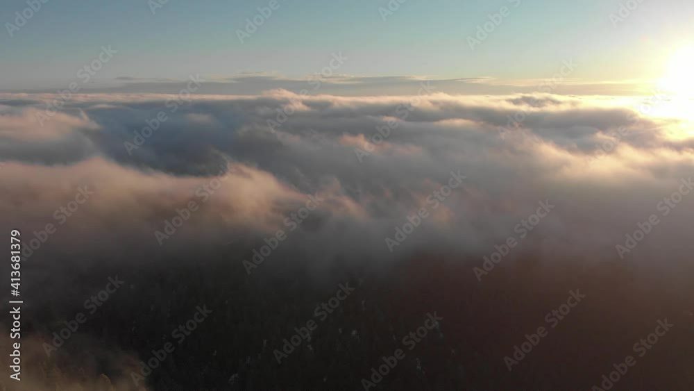 Aerial pan over foggy mountainside sunrise to sun over sea of cloud Aerial pan over foggy mountainside sunrise to sun over sea of cloud