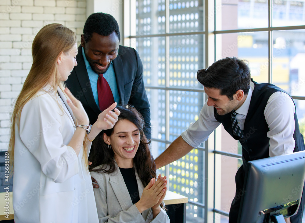 Group of four expertise multiracial businessmen and businesswomen managers clapping their hands with happiness to celebrate a successful company meeting with gathered in front of a desktop computer Group of four expertise multiracial businessmen and businesswomen managers clapping their hands with happiness to celebrate a successful company meeting with gathered in front of a desktop computer