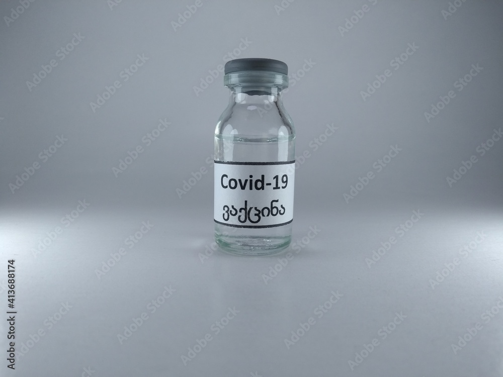 The word COVID 19 vaccine written in Georgian language on a vaccine bottle 