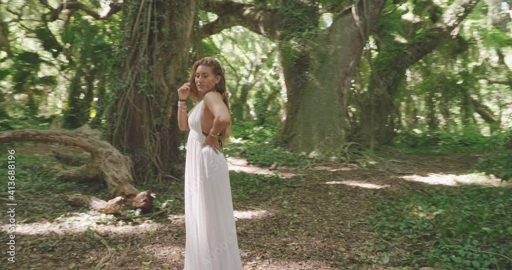 Woman in boho white dress surrounded by tropical jungle in sunlight Woman in boho white dress surrounded by tropical jungle in sunlight
