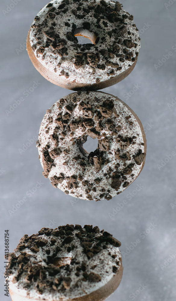 Flying donuts with chocolate pieces on a grey background Flying donuts with chocolate pieces on a grey background