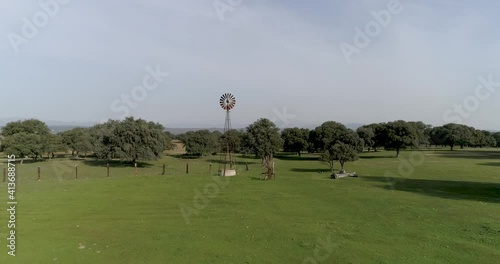 Aerial video Old wind power pump in Spanish farm surrounded by holm oaks photo