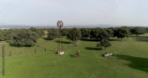 Aerial video Old wind power pump in Spanish farm surrounded by holm oaks photo