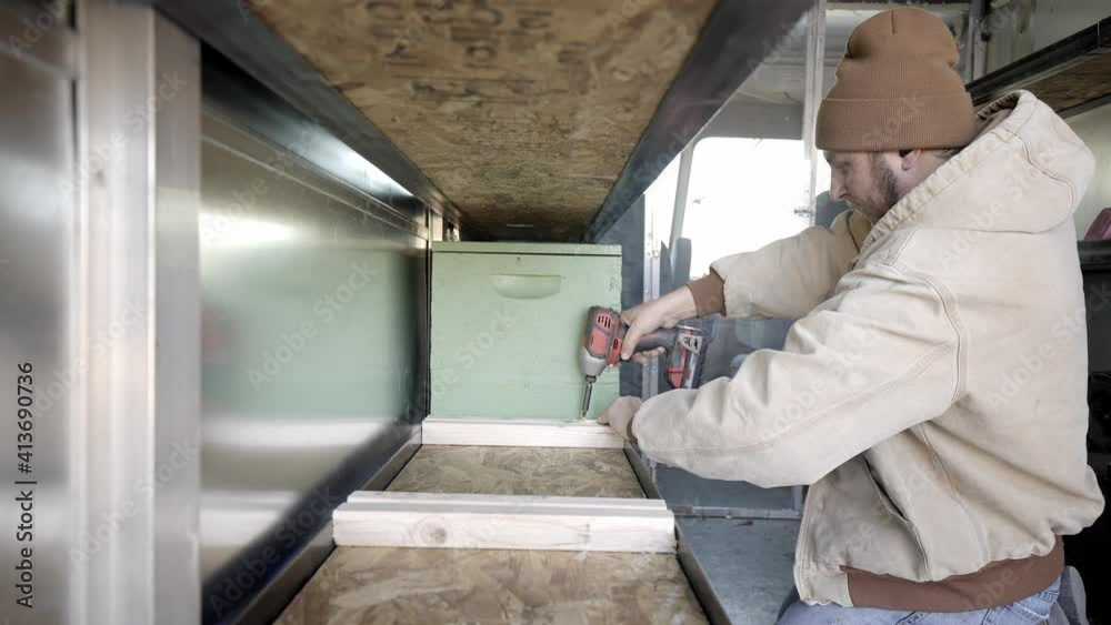 Contractor uses battery powered drill to drill or screw wooden shelves Contractor uses battery powered drill to drill or screw wooden shelves