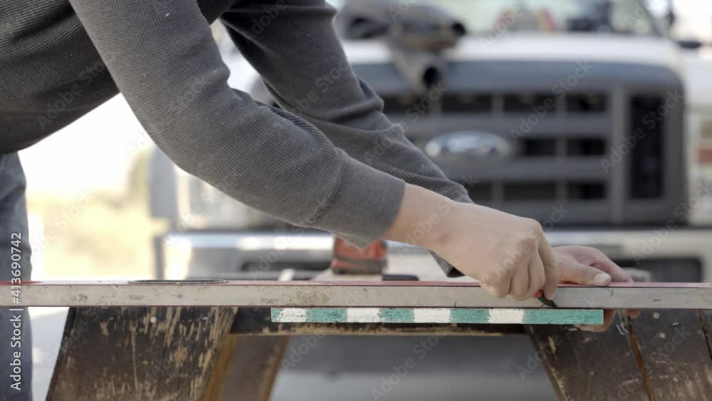 Carpenter hands using pen and ruler or straight edge to mark plank, close up Carpenter hands using pen and ruler or straight edge to mark plank, close up