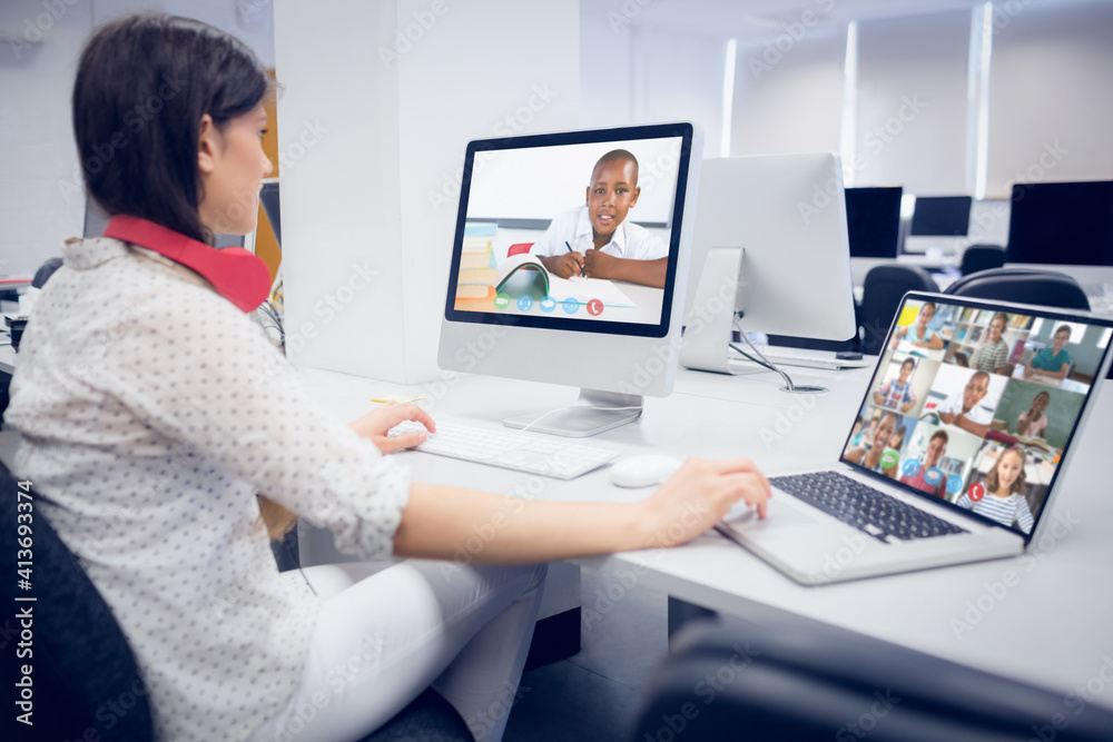 Caucasian female teacher using computer and laptop on video call with school children Caucasian female teacher using computer and laptop on video call with school children