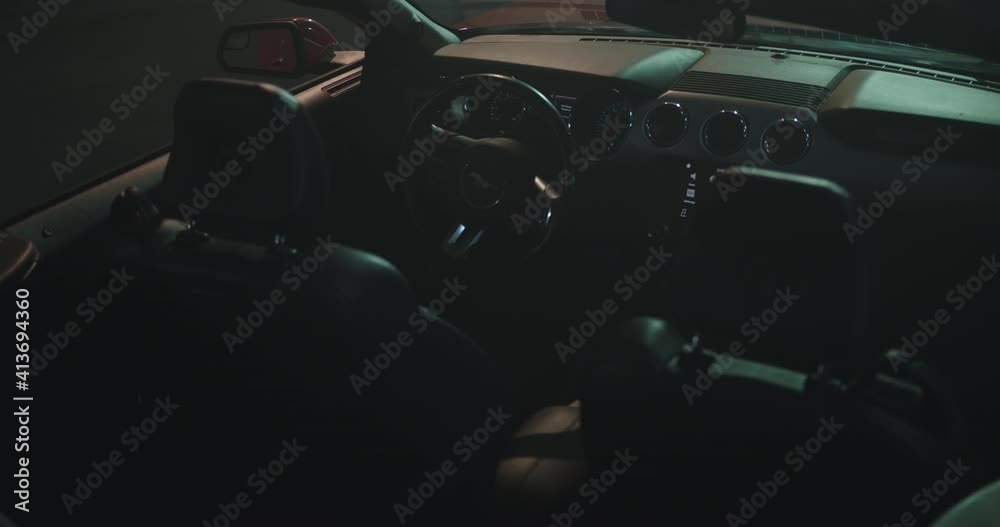 Dashboard, wheel and black interior of a red convertible sports car in a bundle of light. Slowly trucking shot Dashboard, wheel and black interior of a red convertible sports car in a bundle of light. Slowly trucking shot