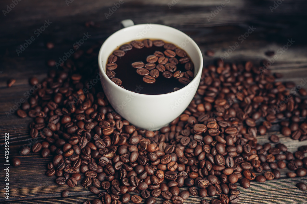 Fototapeta premium coffee beans scattered on a wooden table and a cup with a hot drink aroma
