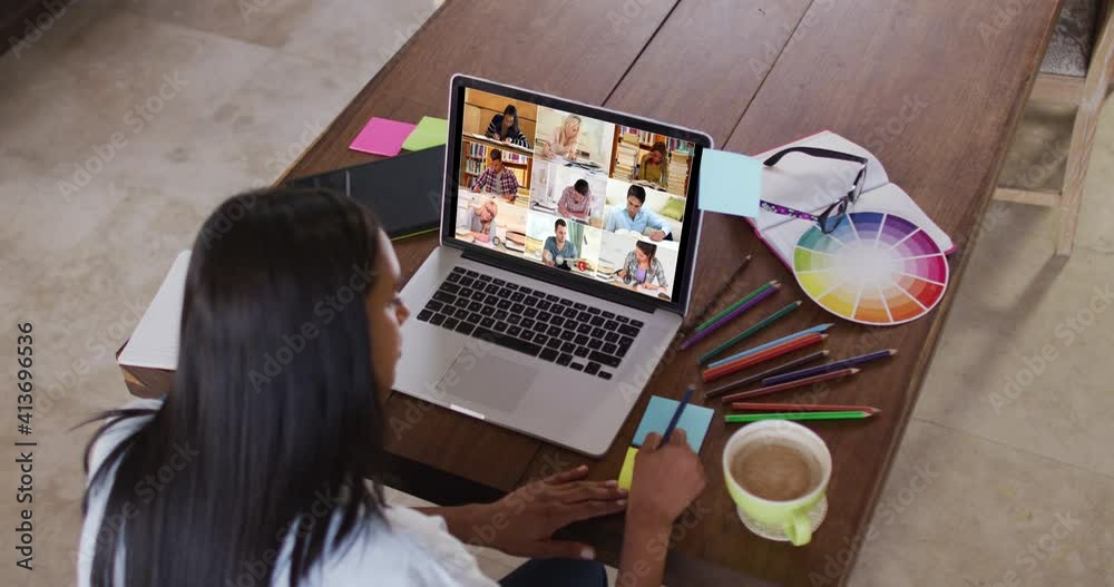 Caucasian female teacher using laptop on video call with students, making notes