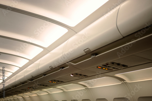 Low angle view of overhead bins in illuminated airplane