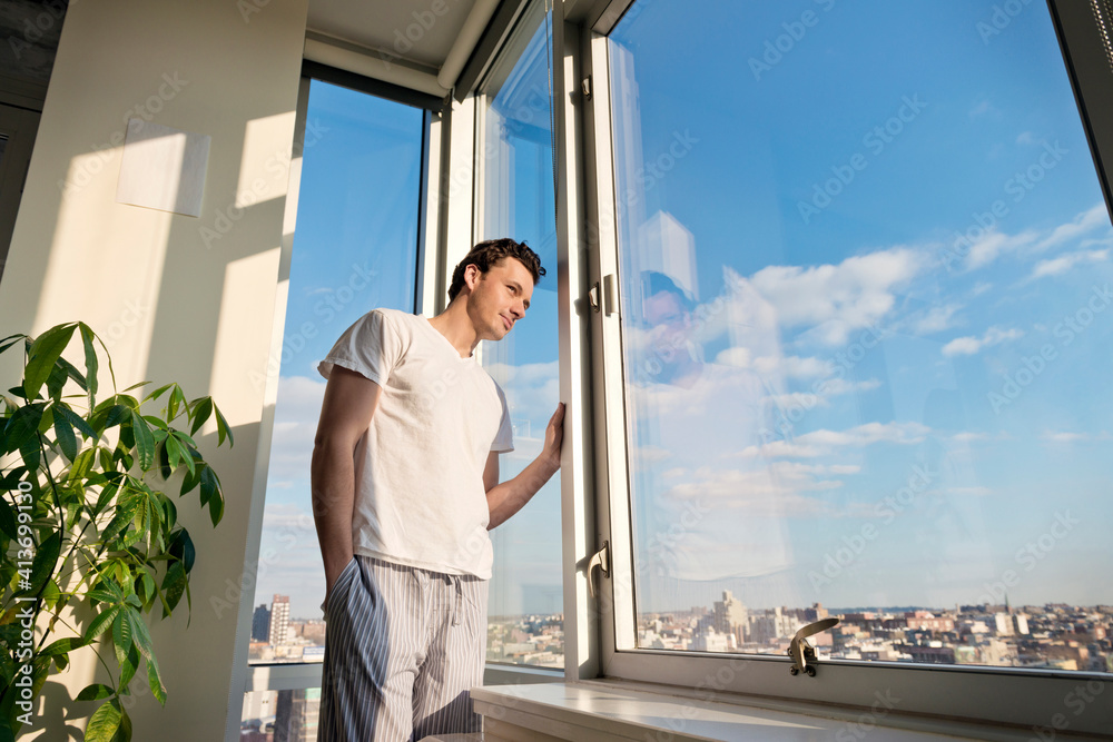 Low angle view of man looking though window at home Low angle view of man looking though window at home