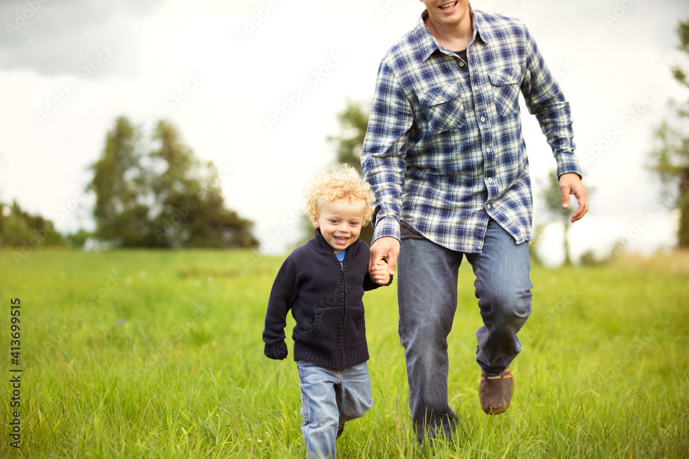 Happy father and son walking on grassy field Happy father and son walking on grassy field
