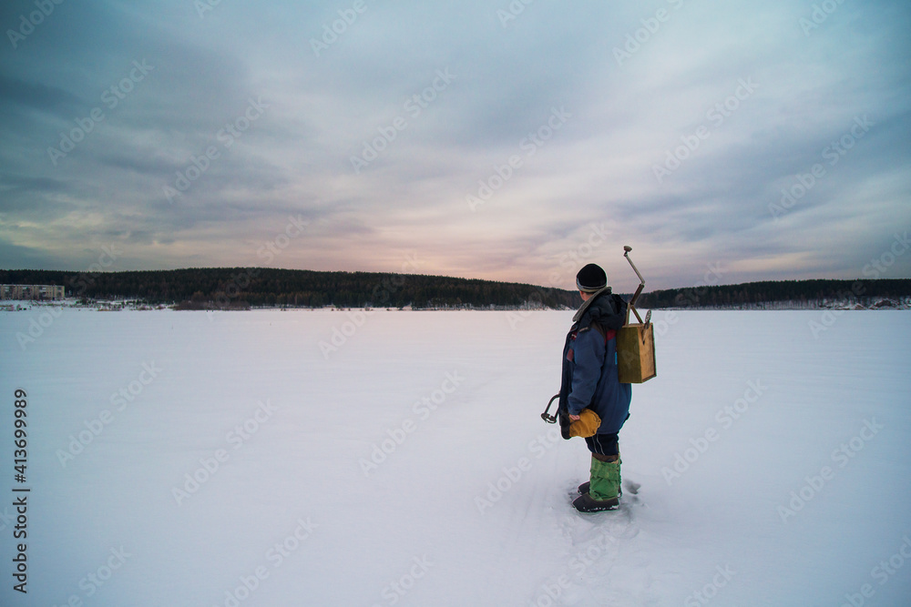 Male holding equipment while standing on frozen lake against cloudy sky Male holding equipment while standing on frozen lake against cloudy sky