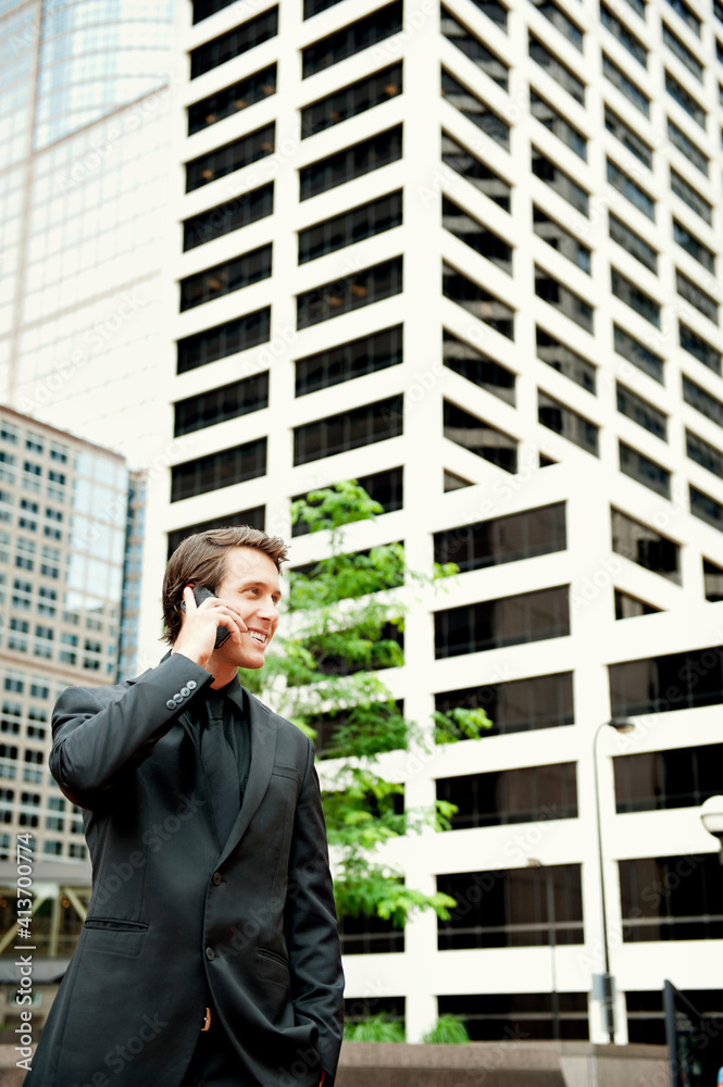 Businessman talking on phone while standing against modern buildings Businessman talking on phone while standing against modern buildings