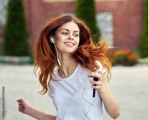 Tablou pe pânză redhead woman outdoors walk headphones fun music