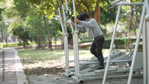 Asian boy about 5 years old doing exercise by using body rider trainer or cycle machine at a public park in Thailand