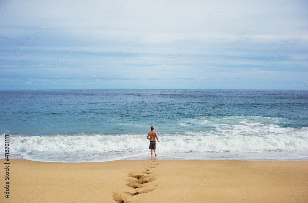Rear view of man running on shore at beach against sky Rear view of man running on shore at beach against sky