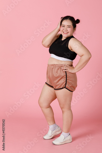 Fototapeta Naklejka Na Ścianę i Meble -  A charming active big body sporty-looking girl in shorts and sport wear standing and smiling with self-confidence and positive face and emotion. Happy and self-esteem concept