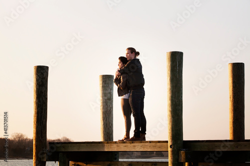 Couple standing on pier against sky during sunset photo